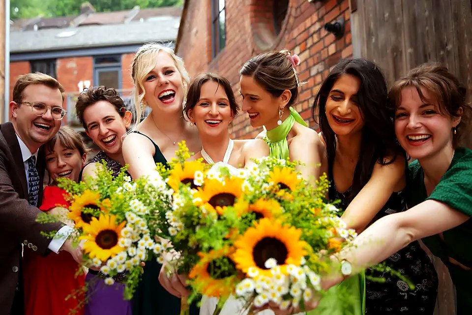Joyful bridal party holding sunflower bouquets