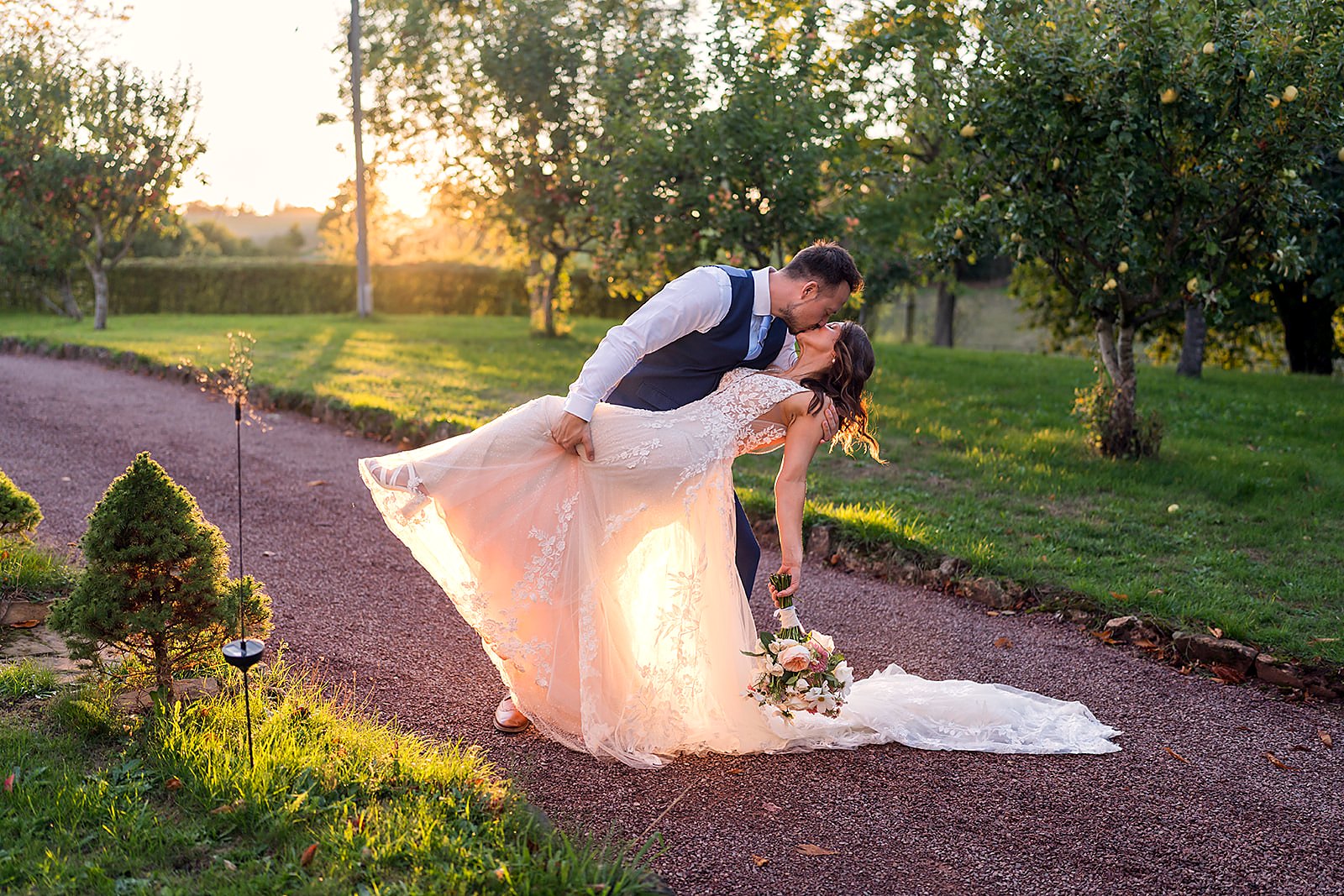 Bride and groom share a golden-hour kiss in an English orchard